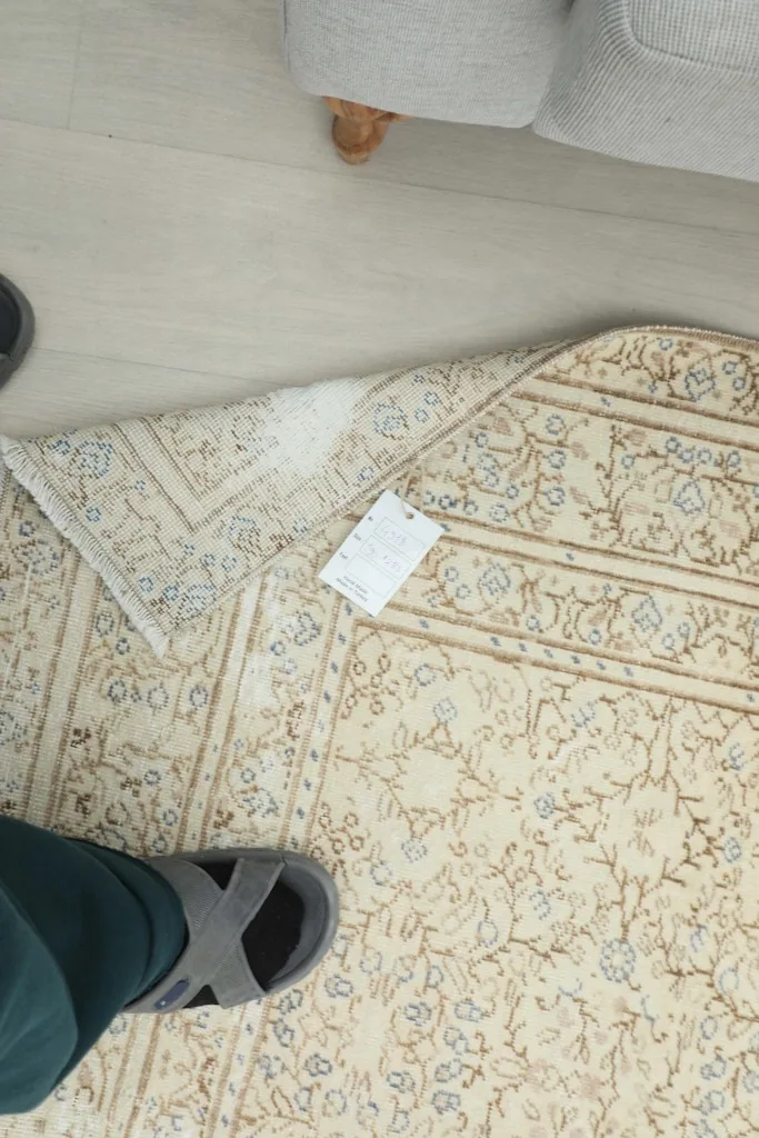 Overhead view showing the rug's back, label, and texture, with feet providing scale