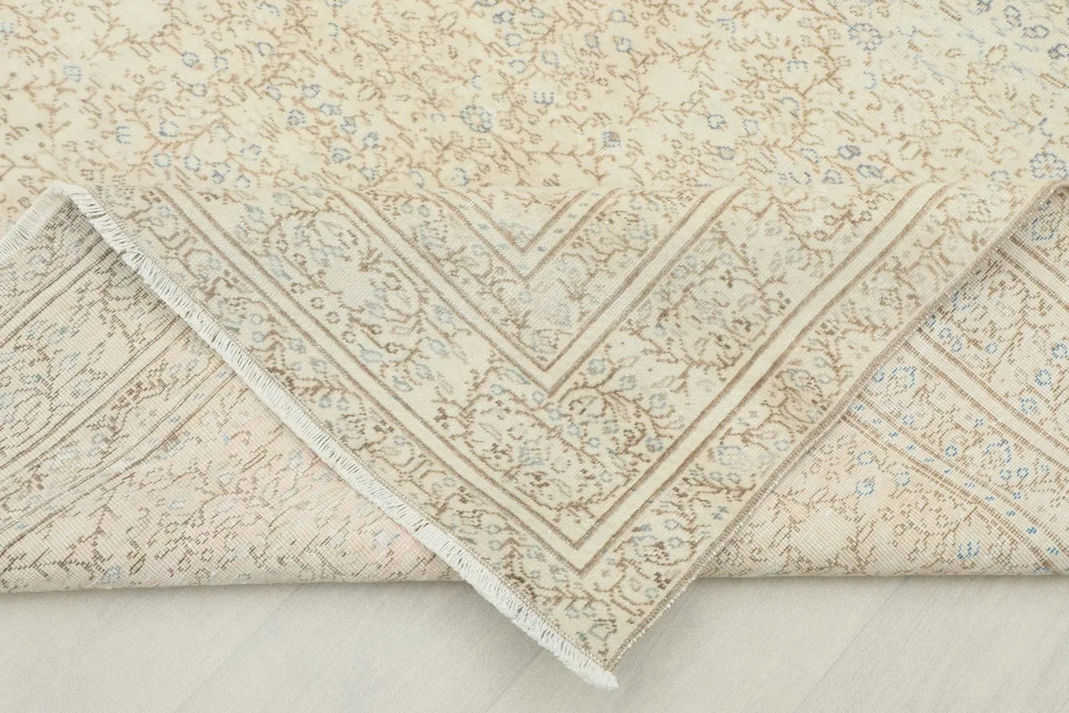 Corner of the rug folded back, revealing the reverse side of the hand-knotted wool on cotton foundation