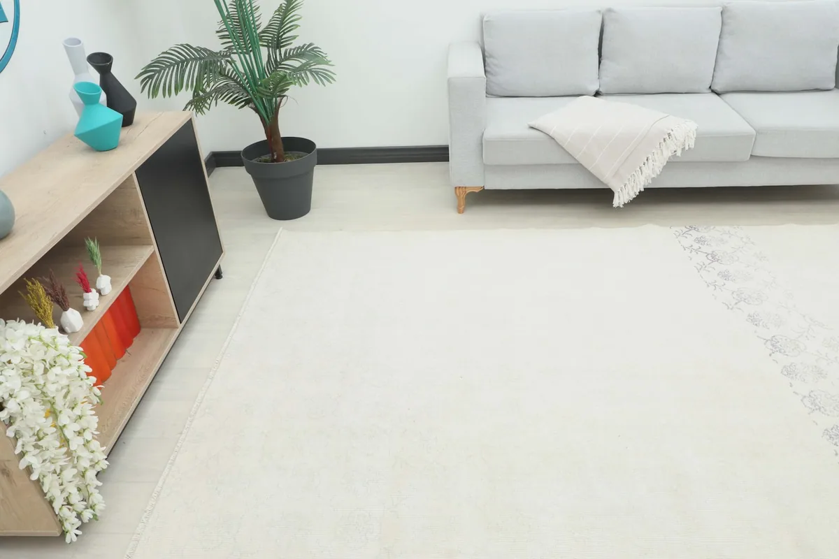 Angle view of the ivory rug in a room setting, showing its placement in front of a gray sofa.