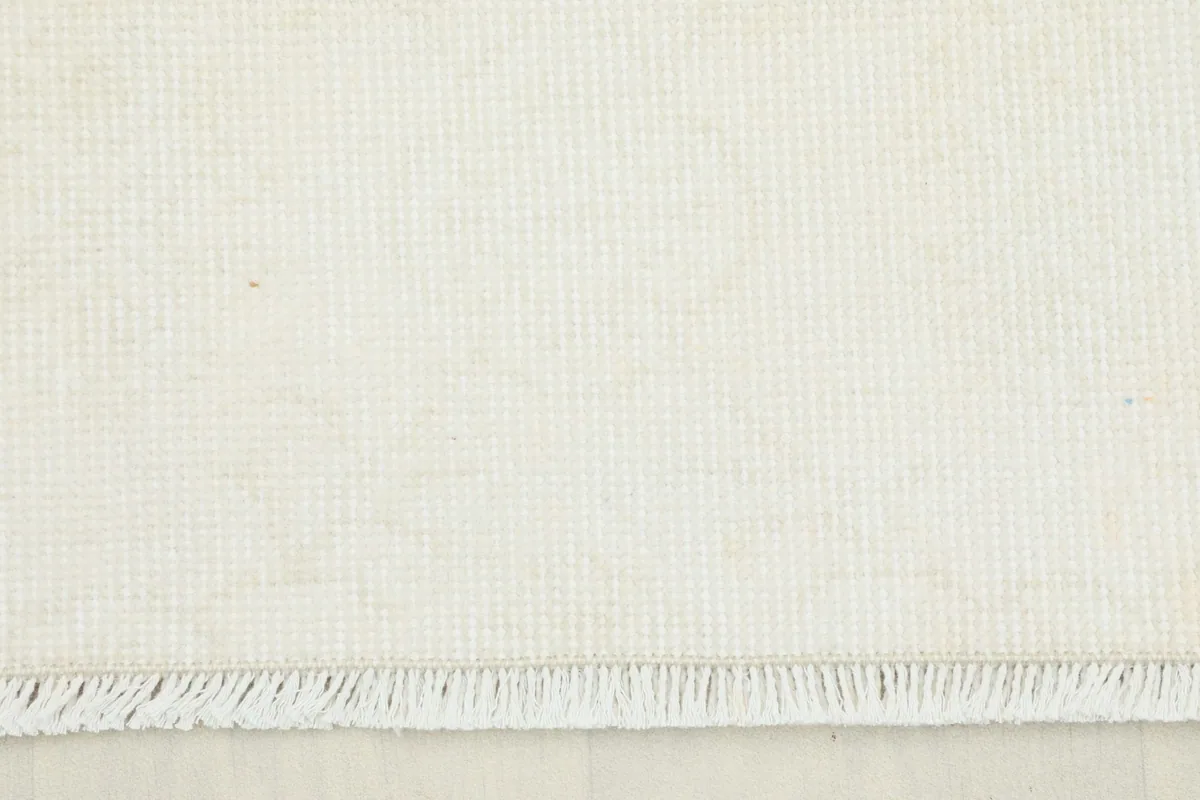 Close-up view of the low pile and texture of the ivory wool rug, showing its hand-knotted quality.