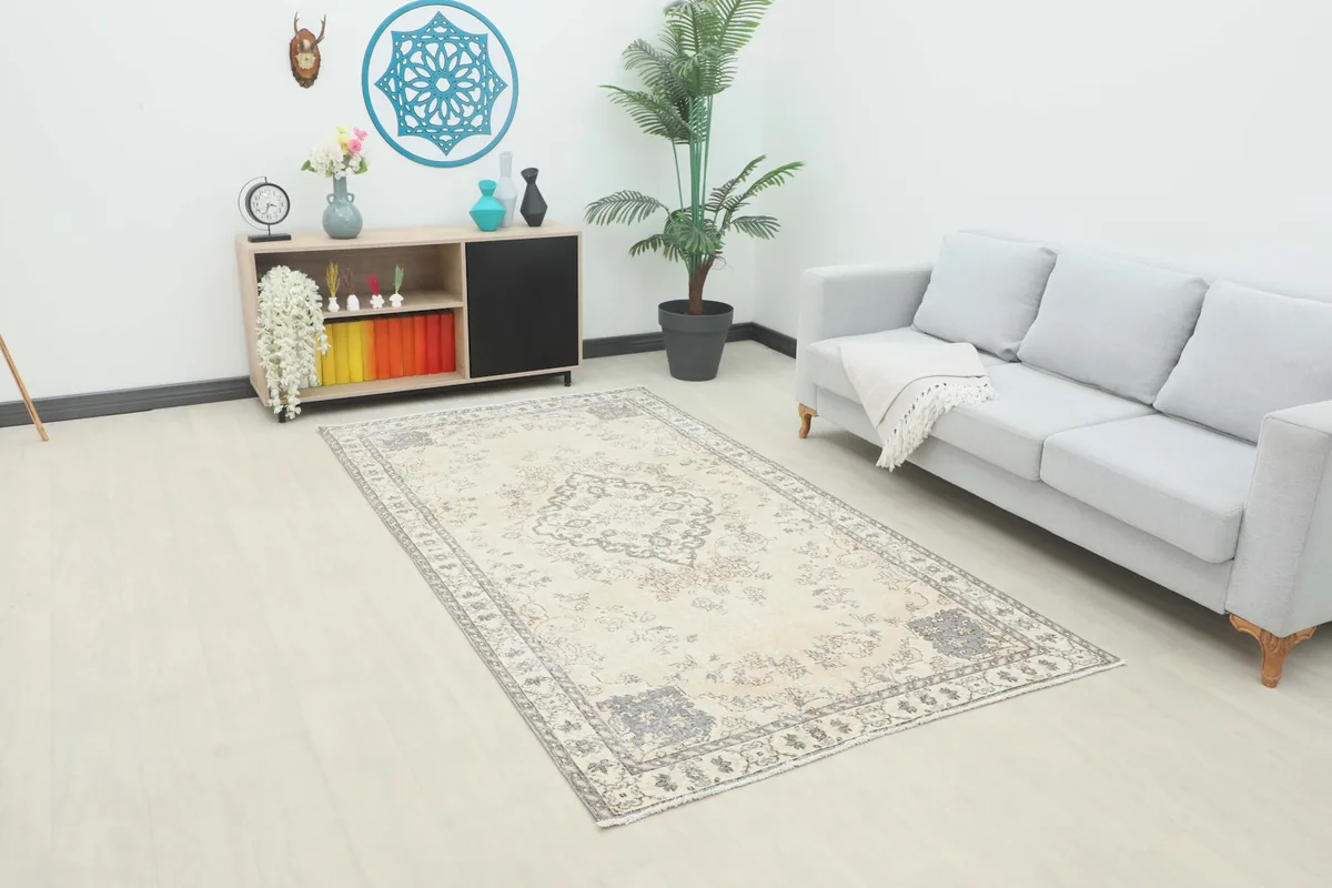 The ivory and gray vintage Anatolian rug laid out in a modern living room setting with a gray sofa.