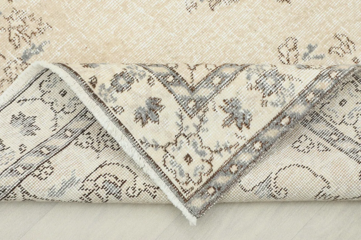 View of the rug folded back, revealing the hand-knotted construction and the reverse side of the pile.