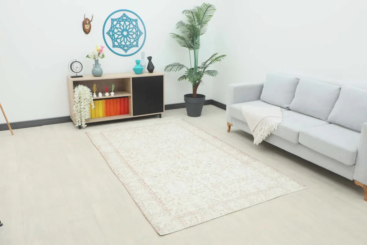 Angled view of the ivory and rose rug in a modern living room setting with a light gray sofa.