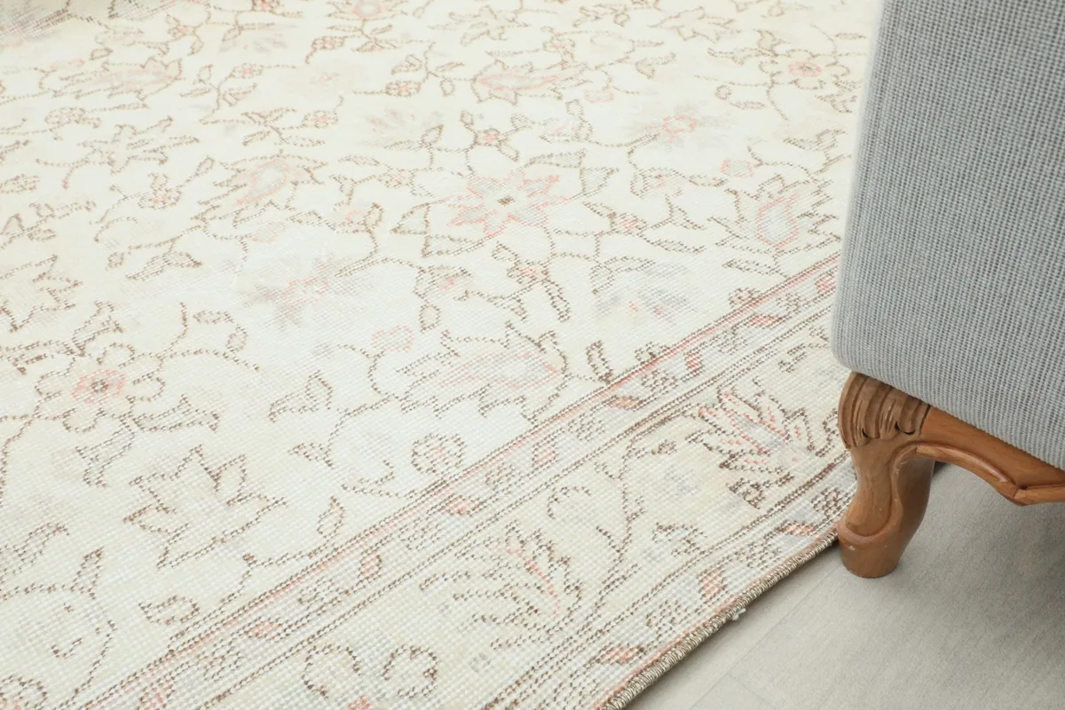 Partial view of the rug on the floor next to a piece of furniture, showing its integration into a space.