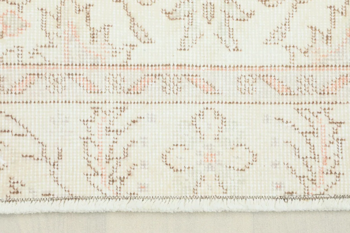 Close-up of the short fringe and the subtle floral and geometric patterns near the rug's edge.