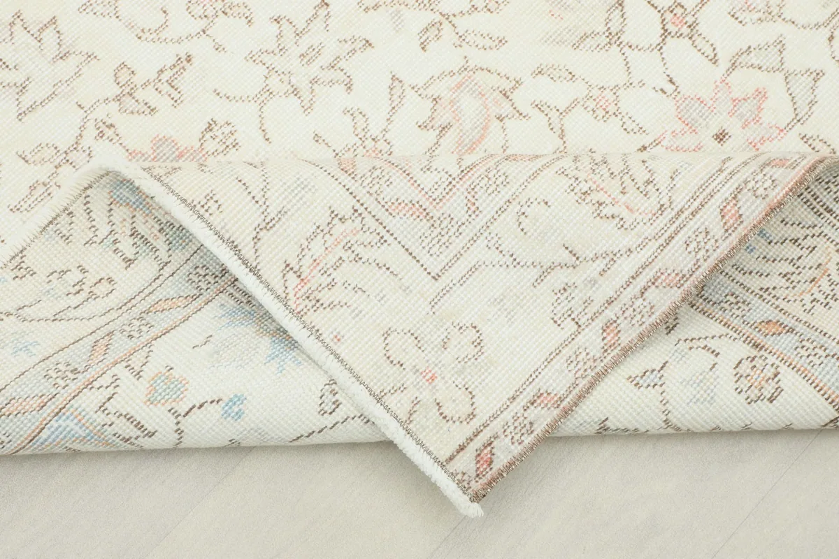 Corner of the rug folded back, revealing the hand-knotted construction and cotton foundation.