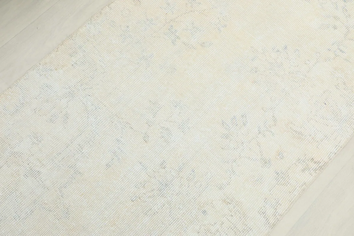 Detailed view of the rug's surface, revealing the faded floral and geometric motifs in blue and gray.
