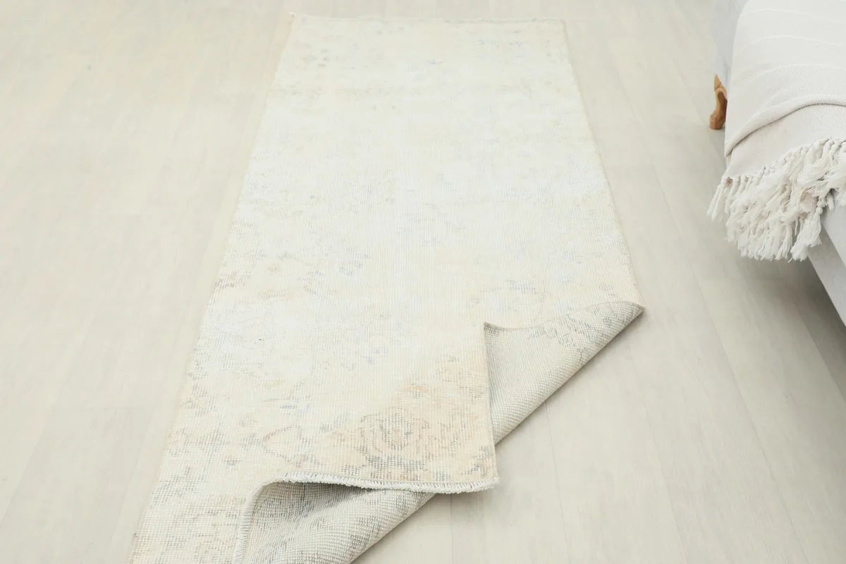 Rug partially folded, revealing the underside and the visible texture of the cotton foundation.