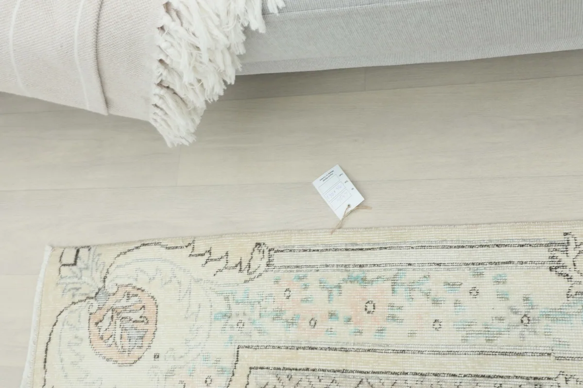 Overhead view of the rug with its tag, next to a rolled rug