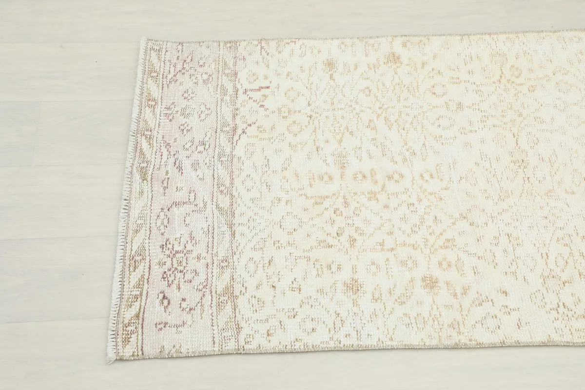 Close-up angle view of the other end of the cream runner rug, highlighting subtle patterns and texture.