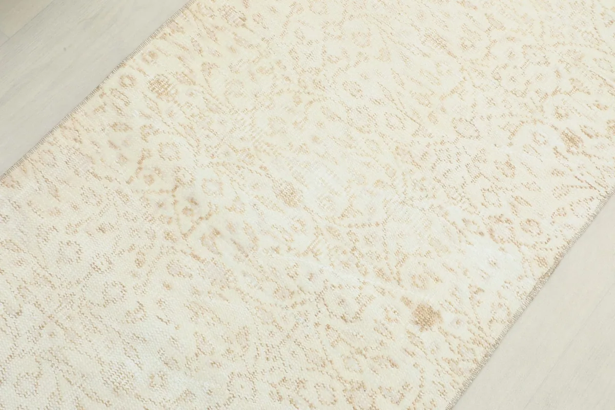 Detailed view of the central field of the cream rug, showing the subtle floral and geometric motifs.