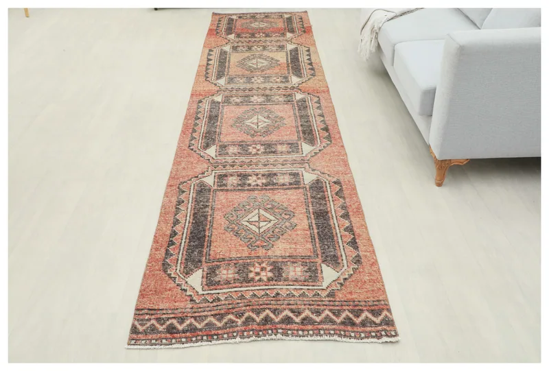 Full top view of a rust and brown geometric vintage Anatolian runner on a white background.
