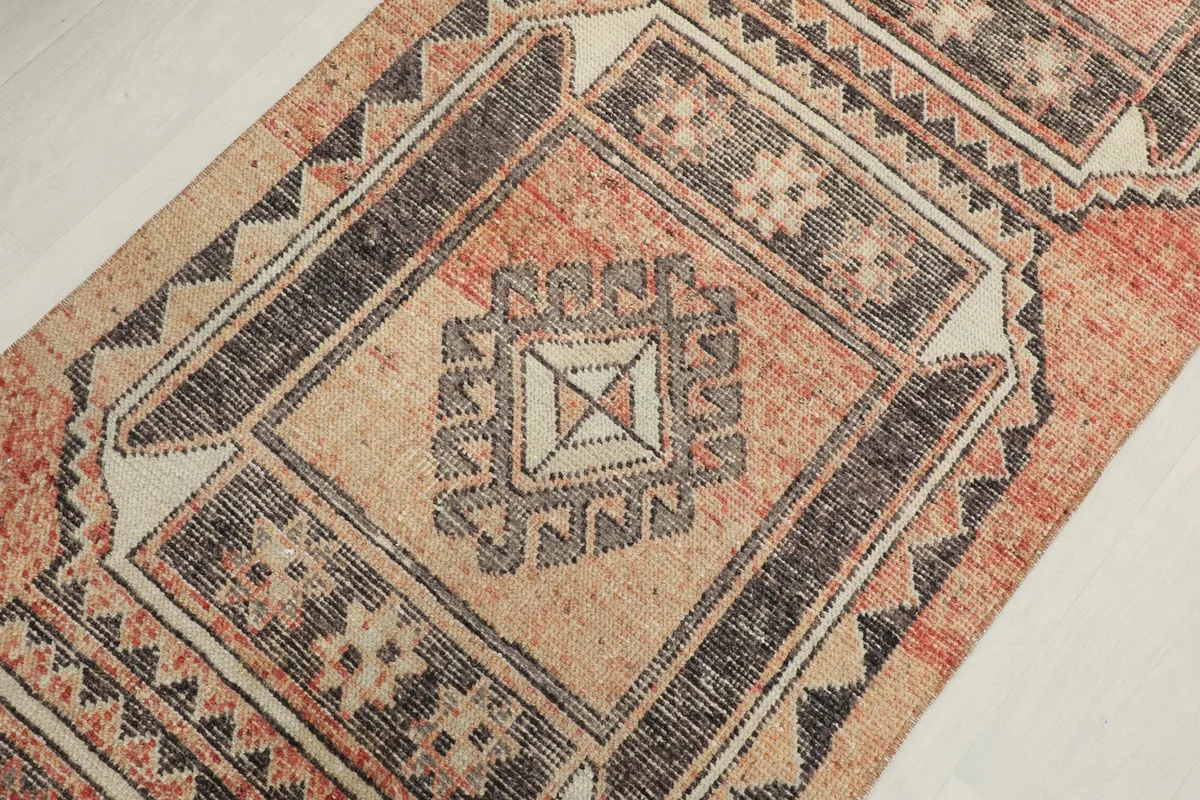 Overhead close-up of a central geometric medallion with cream and black details on the rust field.