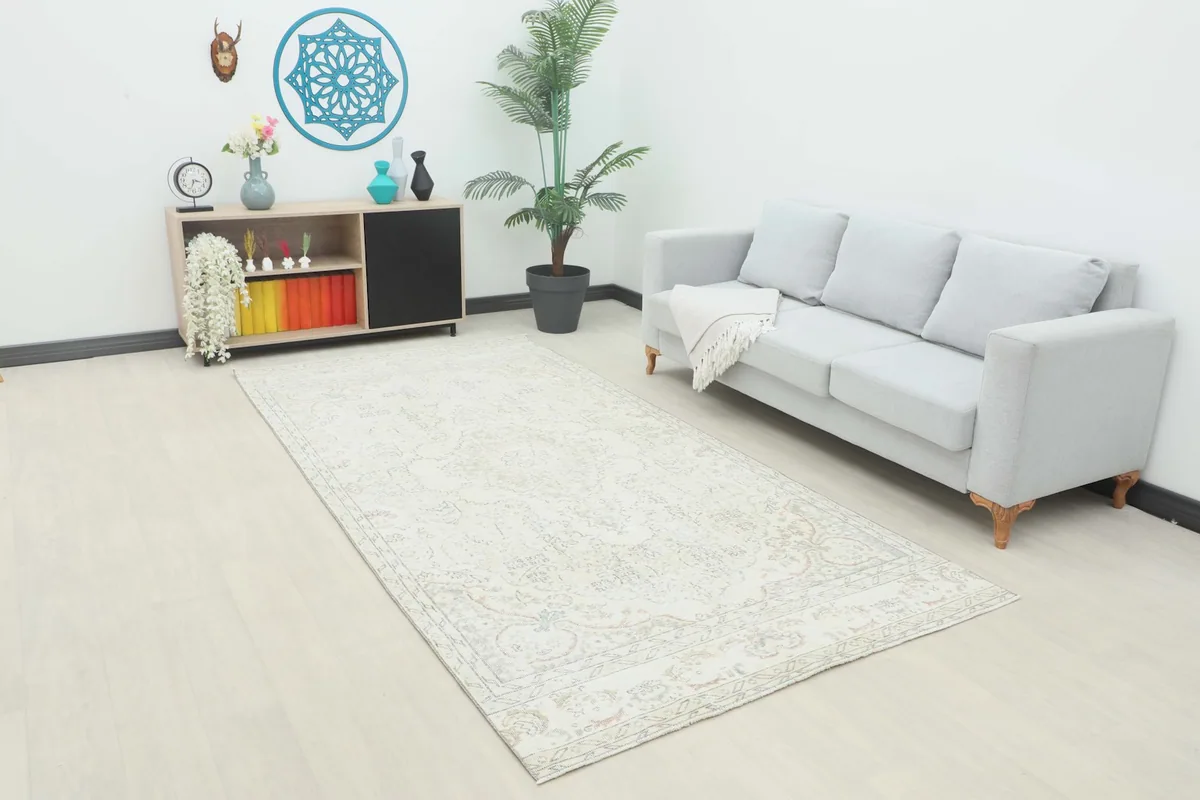 Ivory vintage rug displayed in a living room setting with a sofa and cabinet