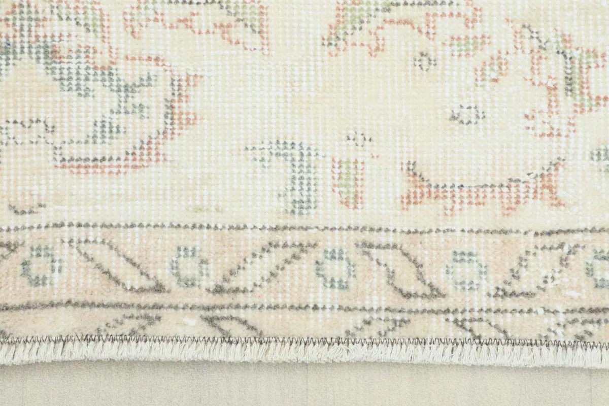 Close-up of the rug's border showing subtle beige, gray, and rose patterns