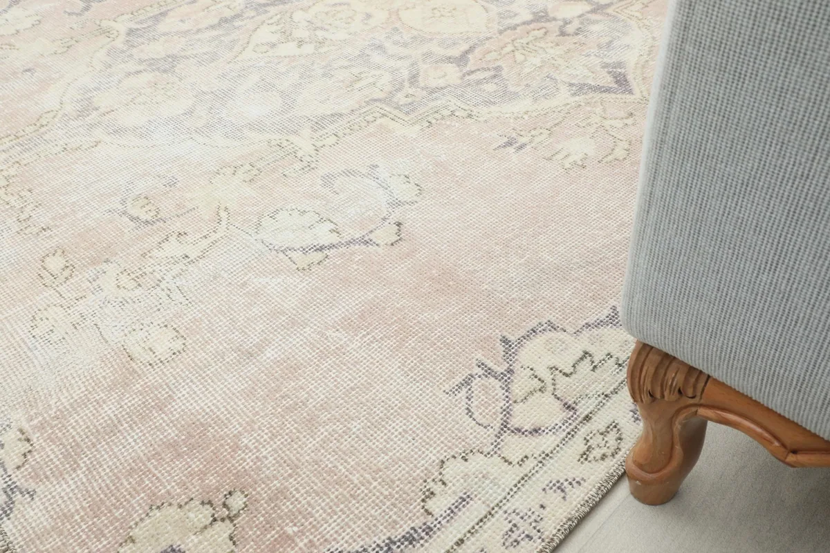 Corner of the Muted Rose Medallion Anatolian rug next to a piece of furniture, showing scale.