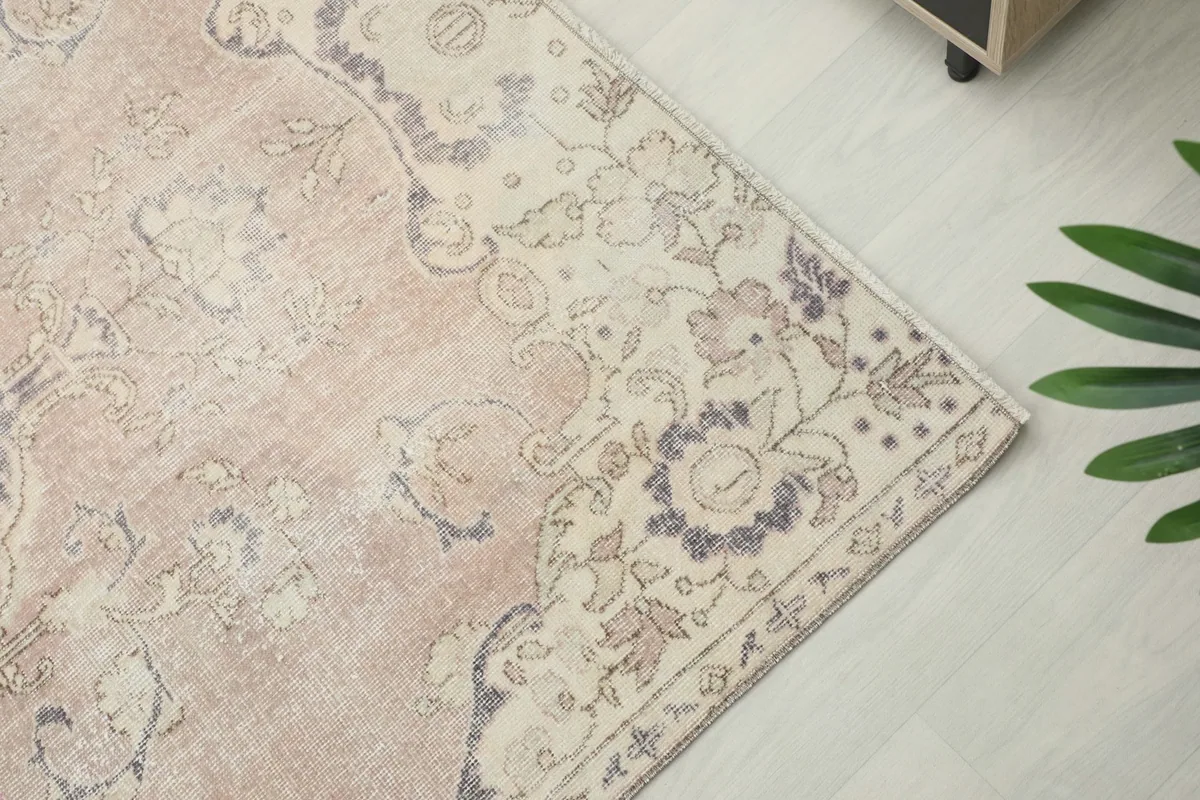Close-up of the rug's border, showcasing the faded floral patterns and ivory details.