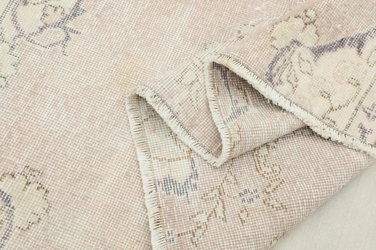 Folded section of the rug showing the low pile texture and subtle color variations.