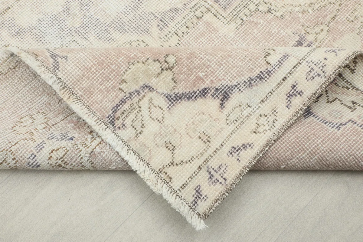 Corner of the rug folded back to reveal the hand-knotted wool pile and cotton foundation.