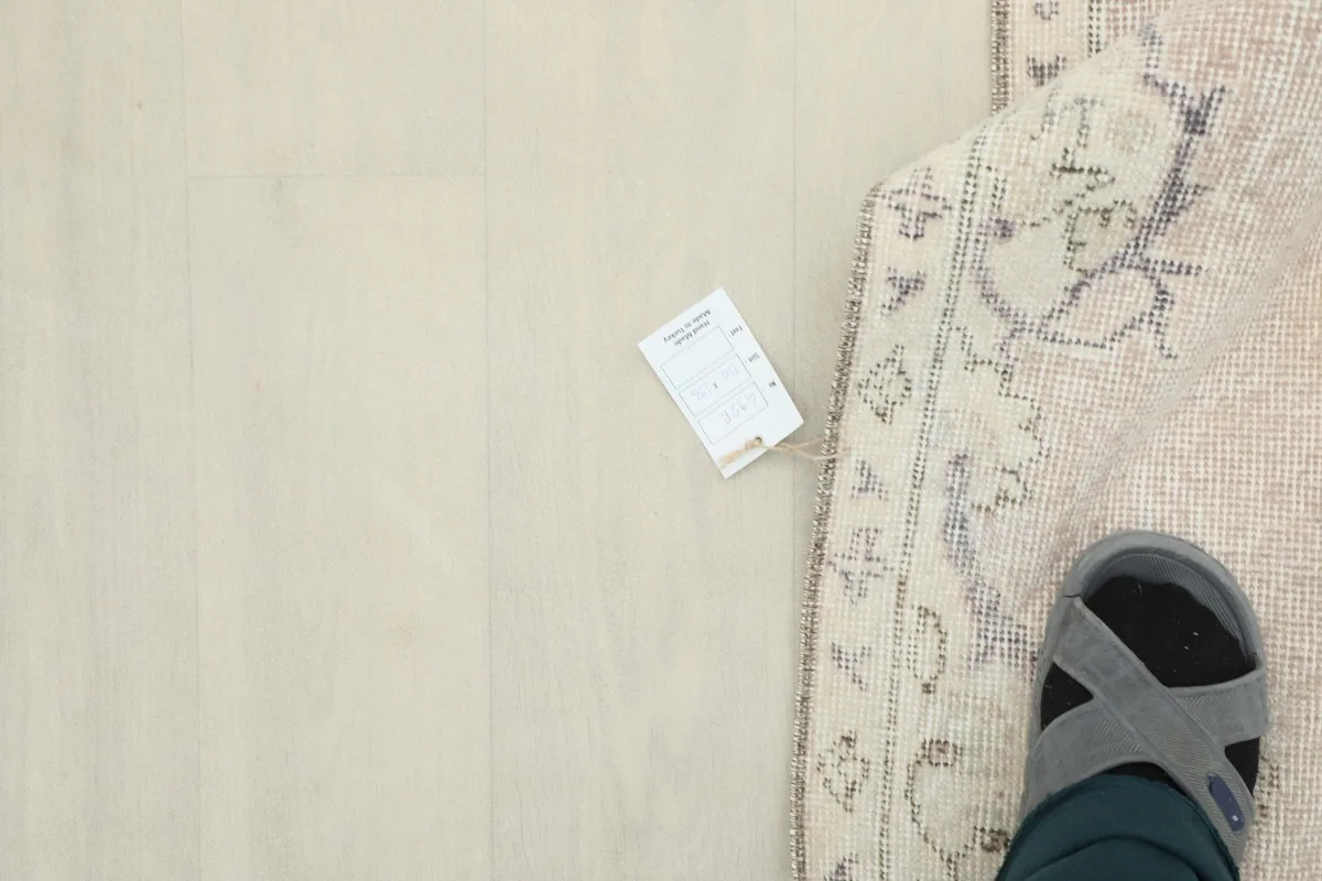 Overhead shot of a foot next to the rug, with a measurement card for scale indication.