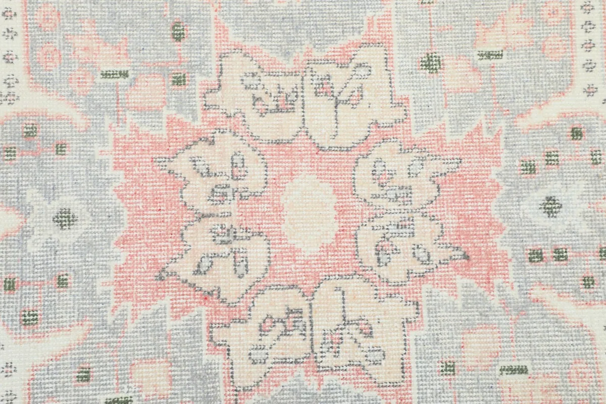 Close-up of a section of the medallion showing variations in rose and gray tones and wool texture.