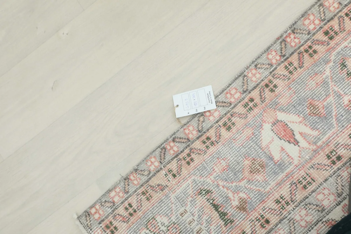 Detail of the rug's edge and a product tag, indicating its origin and material.