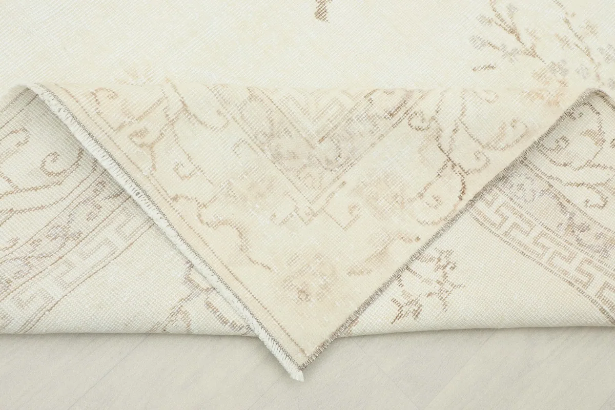 Corner of the rug folded back to show the cotton foundation and the reverse side of the hand-knotted construction.
