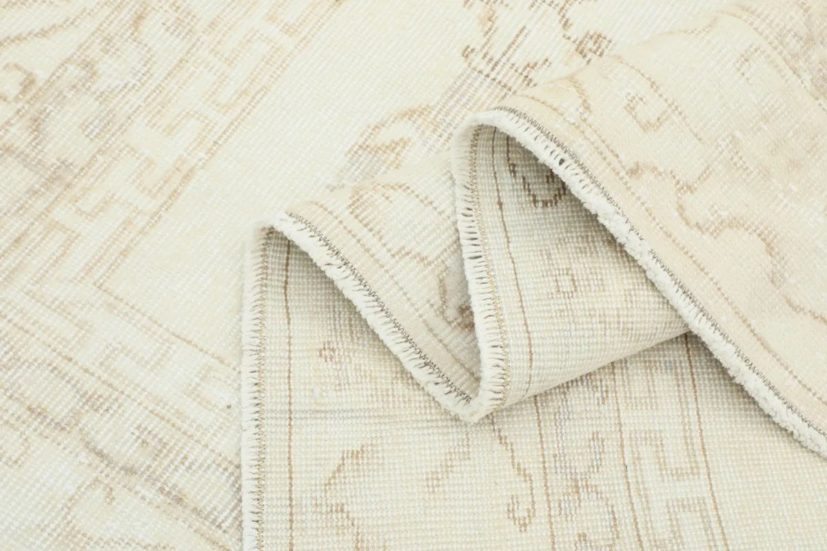 Close-up of the rug's edge folded, revealing the tight weave and low pile characteristic of vintage wool rugs.