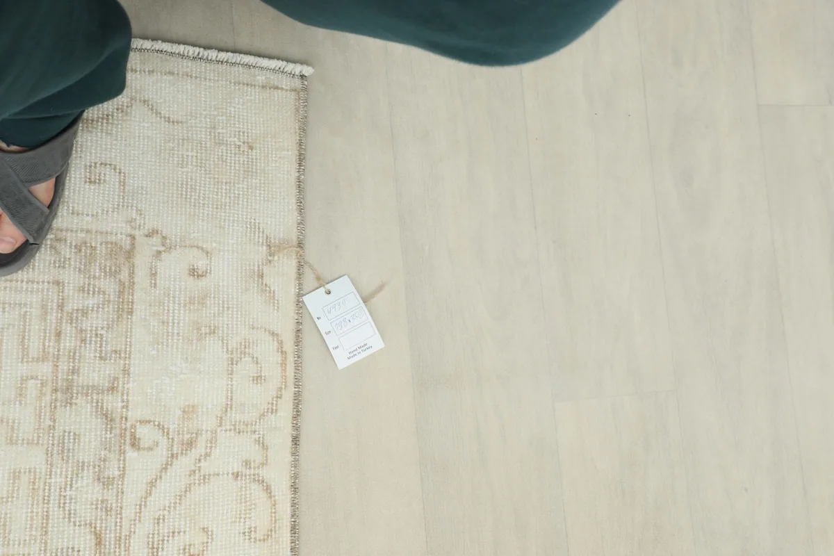 Overhead view of a small section of the rug, showing the tag and a person's foot for scale.
