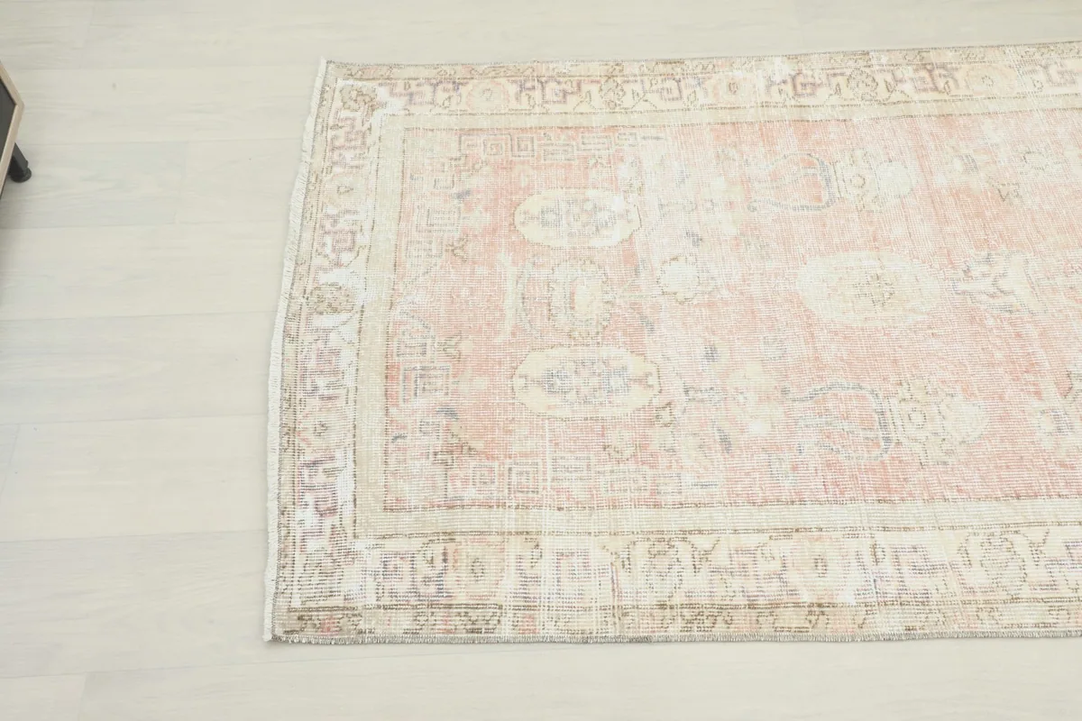 Angled detail of the rug's center, revealing the subtle medallion and geometric patterns within the rose field.