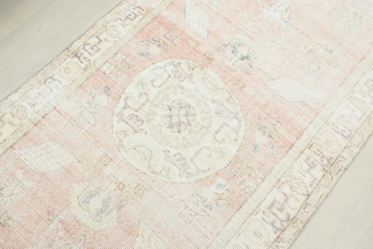 Detailed overhead shot of a central medallion motif on the rose field, showing color variations and wear.