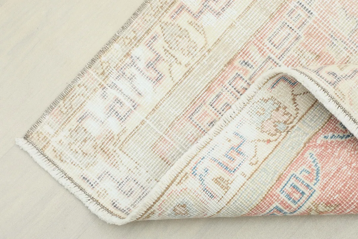 Corner of the rug folded to reveal the cotton foundation and the reverse side of the hand-knotting.
