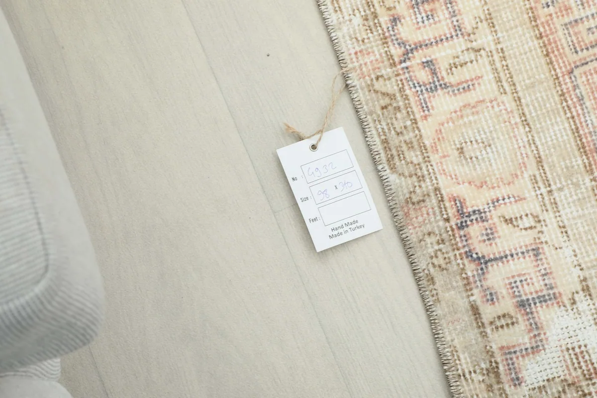 Rug tag showing product information and origin, placed next to the edge of the vintage Anatolian runner.