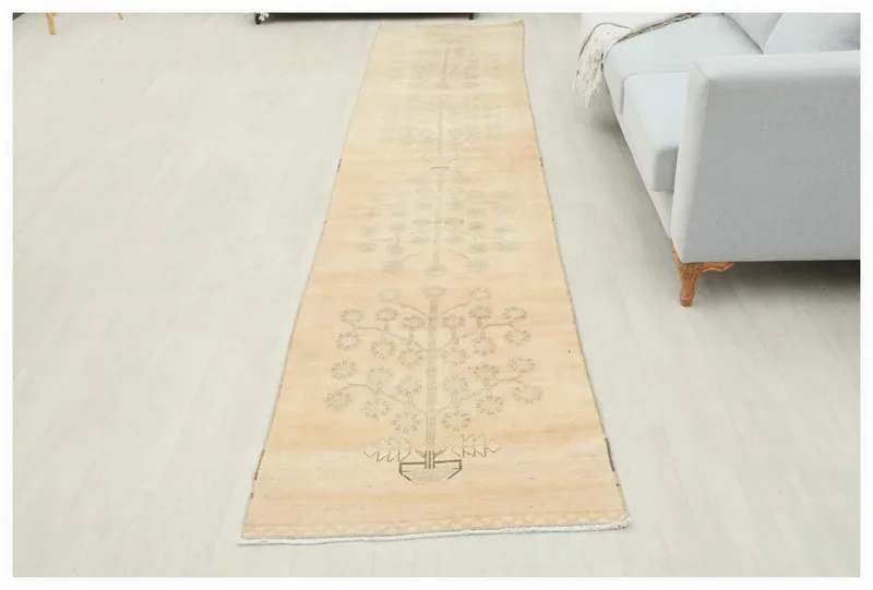 Full top view of the vintage beige and tan Anatolian runner rug on a white floor