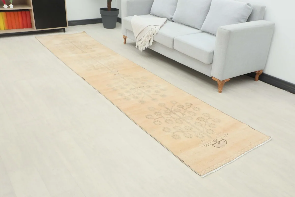 Angled view of the beige runner rug stretching across a room next to a light gray sofa
