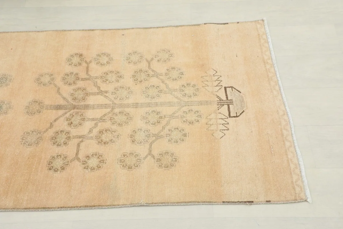 Close-up view of one end of the runner rug, showing the tan tree motif on a beige field