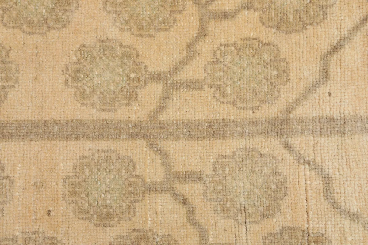 Extreme close-up of the low pile and texture of the hand-knotted wool rug, showing the tan motif