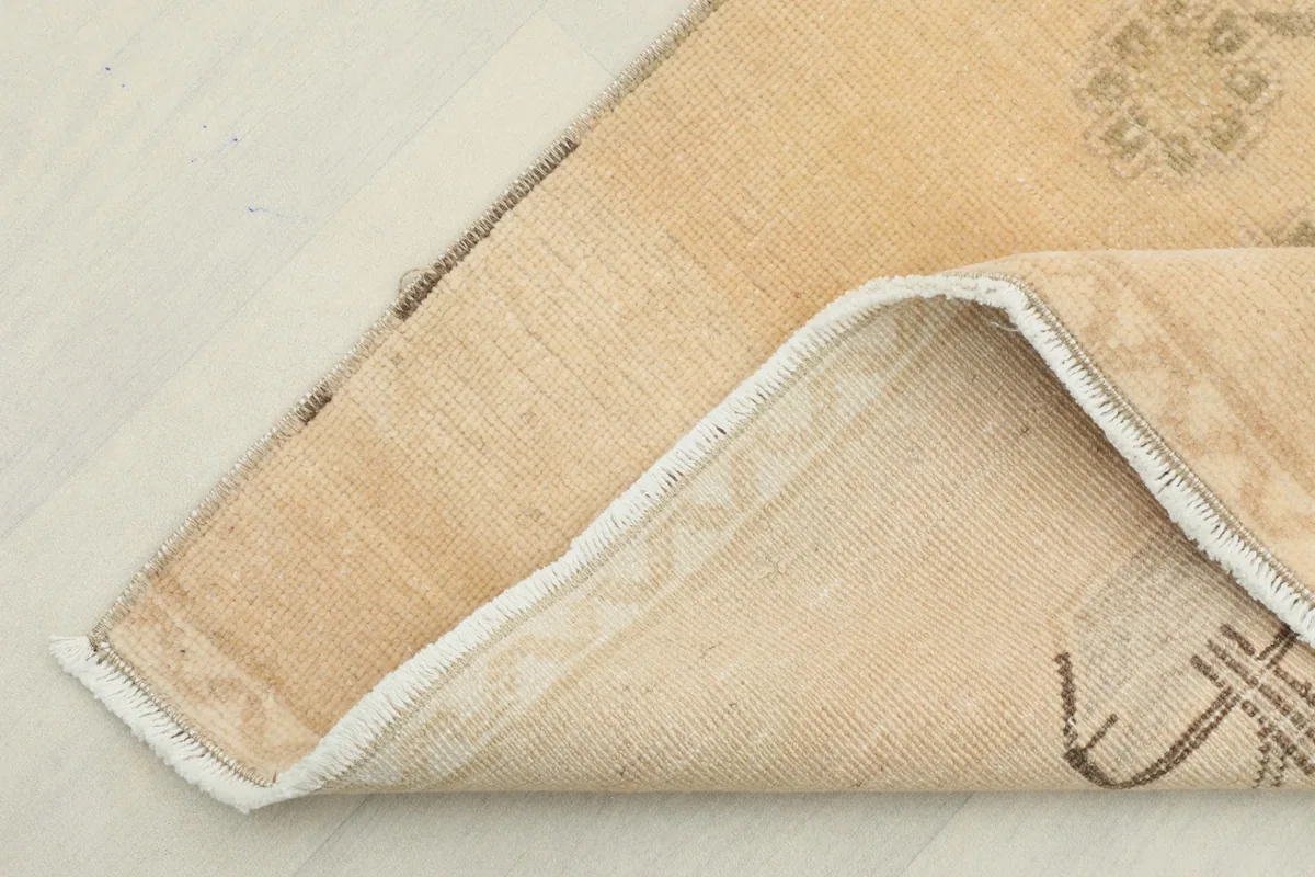 Corner of the rug folded back, revealing the cotton foundation and hand-knotted construction