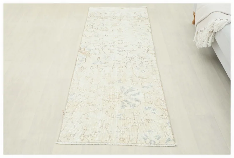 Full top view of the 2'3" x 6'9" ivory and blue floral vintage Anatolian runner rug on a white background.
