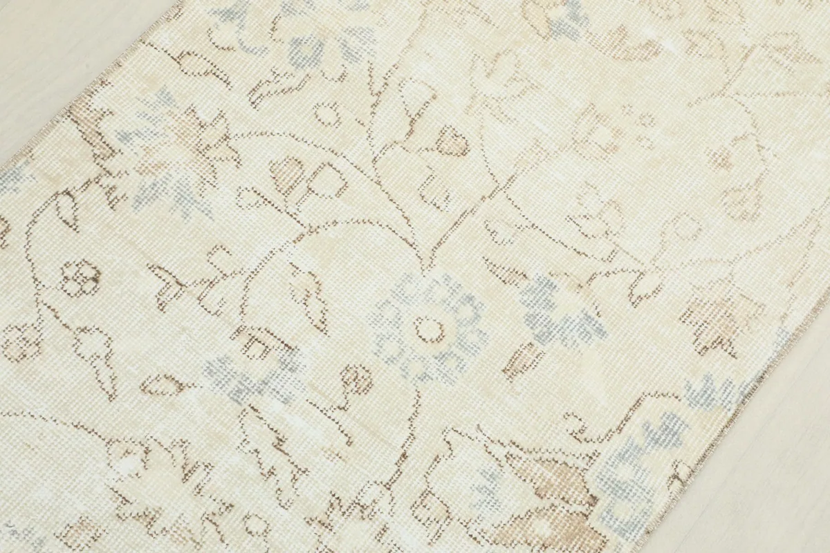 Macro view of the floral motifs and the worn, low pile texture of the vintage runner.