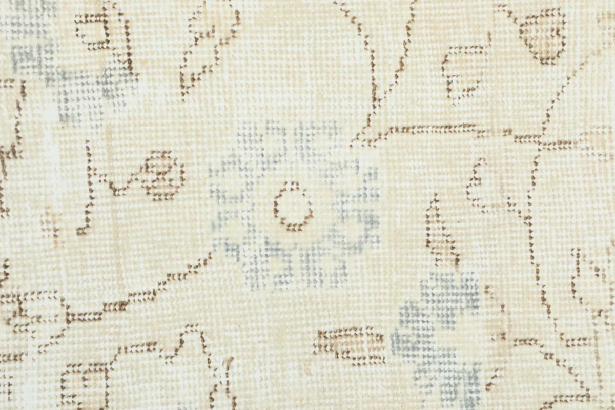 Extreme close-up of the rug's low wool pile, revealing individual knots and muted colors.
