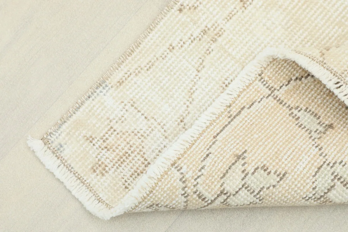 Corner of the rug folded to show the cotton foundation and the reverse side of the hand-knotted construction.