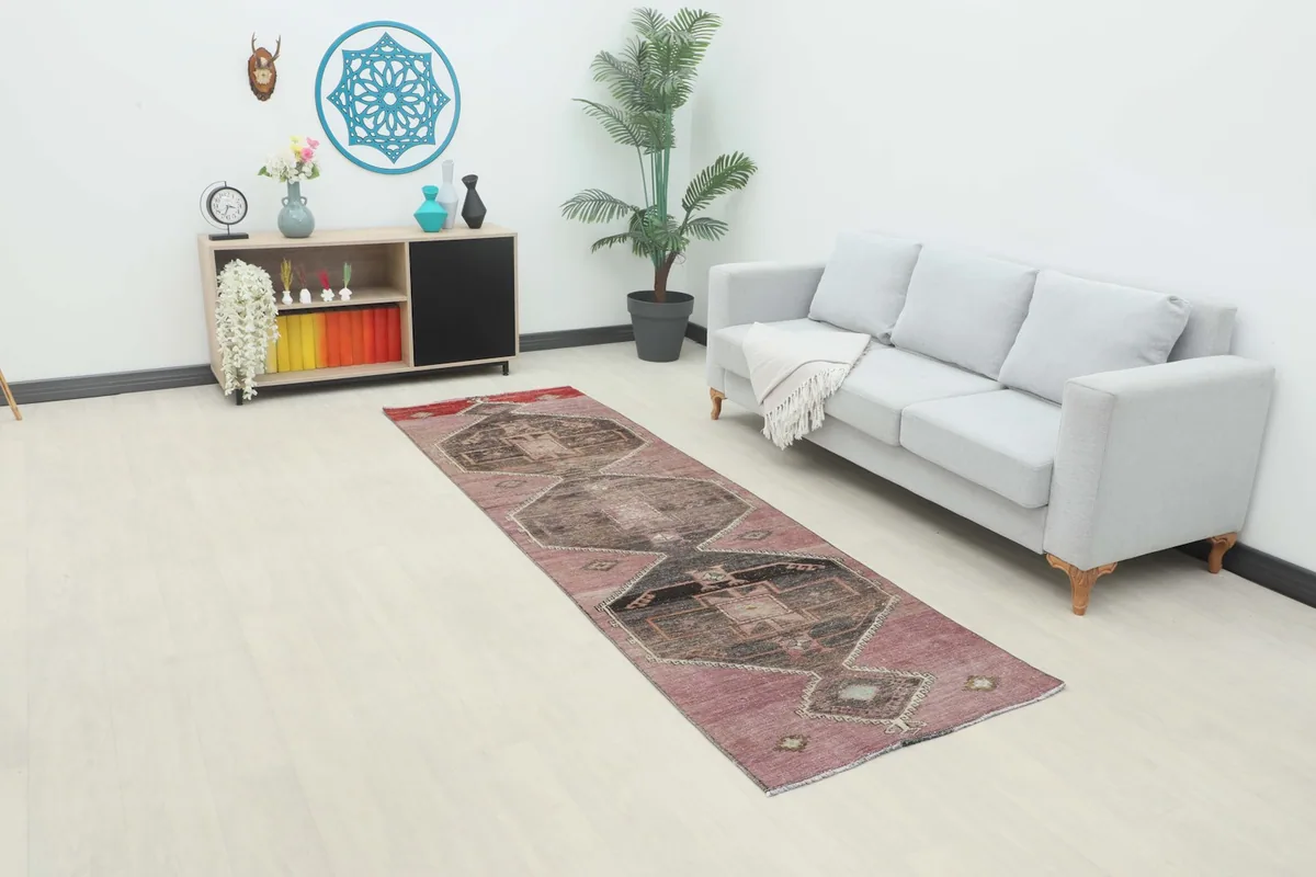 Rose and charcoal geometric runner rug placed in a modern living room setting next to a gray sofa