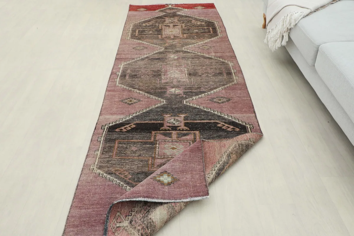 Runner rug partially folded in a room setting, displaying its overall design and length