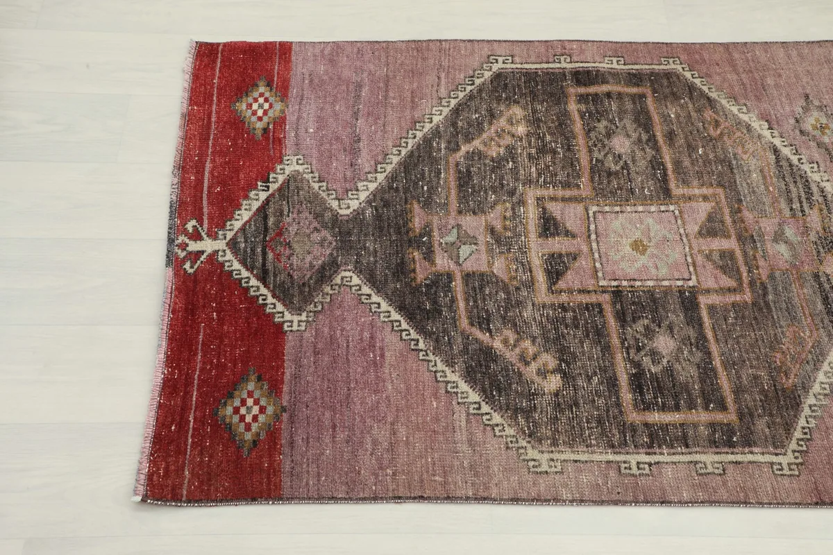 Detailed view of one end of the runner, showing the red border and part of a charcoal medallion