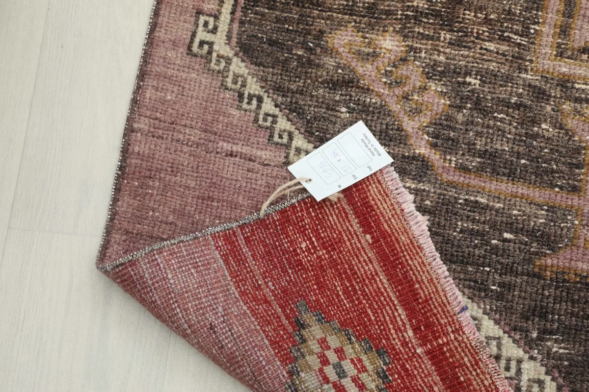 Corner of the rug folded to show the back, highlighting the red section and the care label