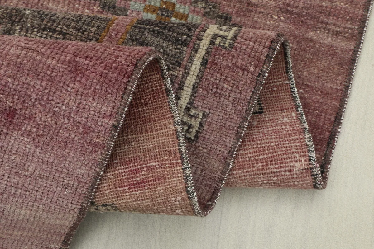 Close-up of the rug folded, revealing the texture of the low wool pile and the construction