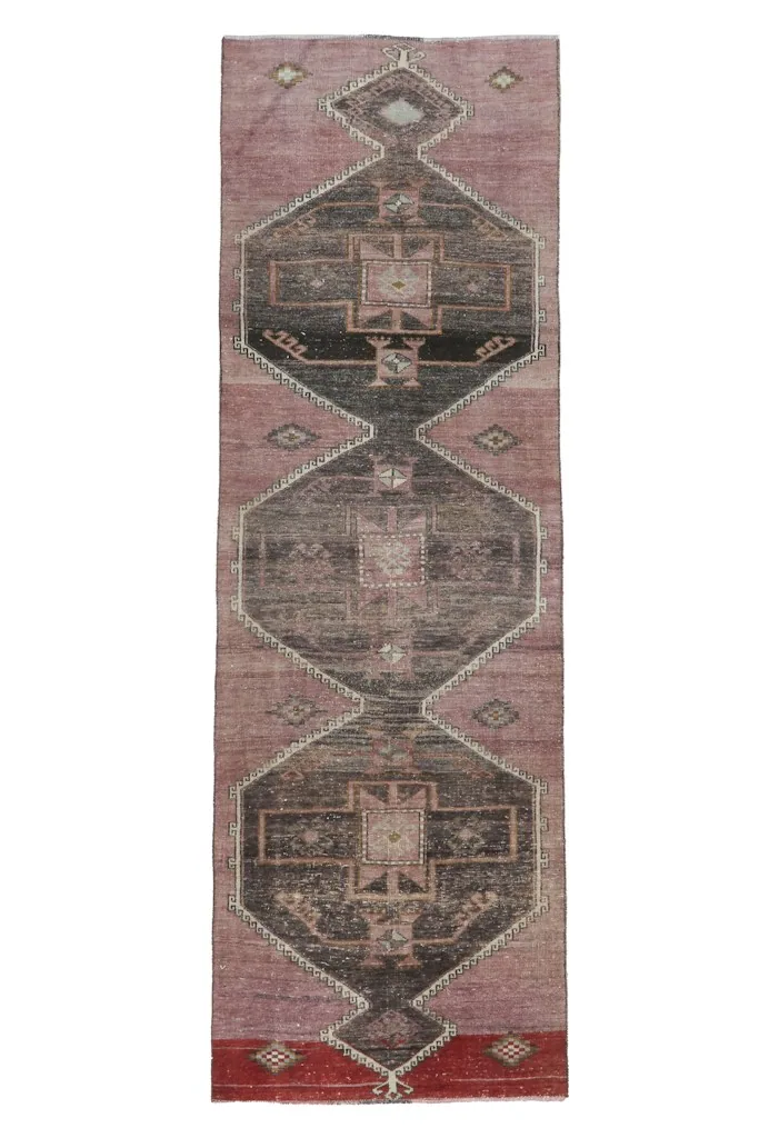 Full overhead view of the rose and charcoal geometric vintage Anatolian runner rug on a white background