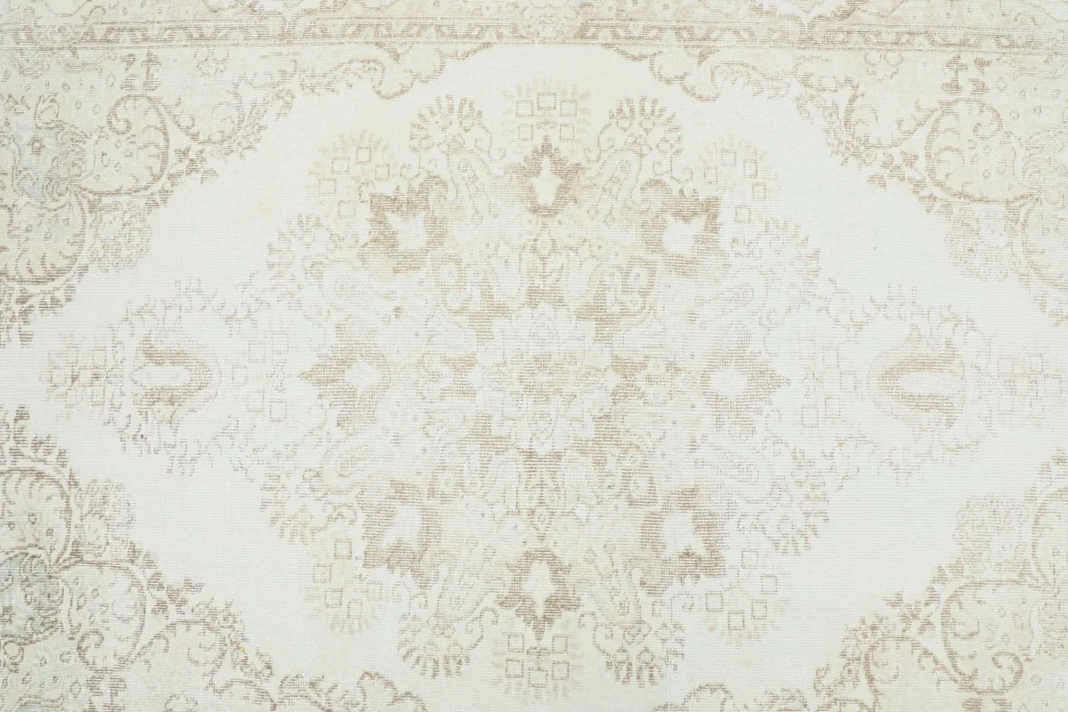 Detailed view of the central medallion motif in beige and tan against the ivory field.