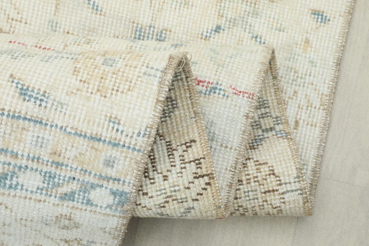 Close-up of the rug folded, showing the intricate knotting on the reverse and the worn pile.